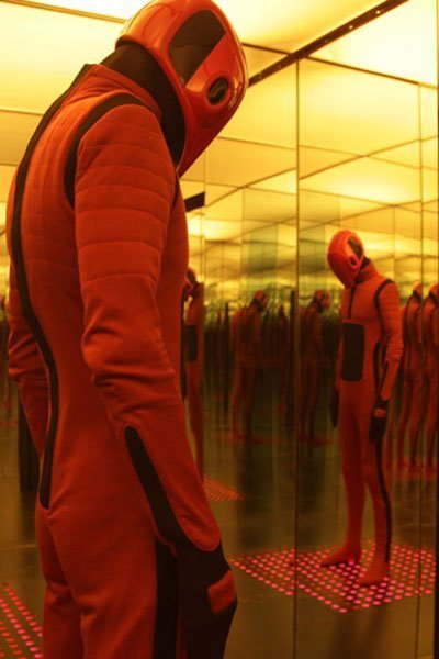 A sentionaut stands dormant in a room full of mirrors.