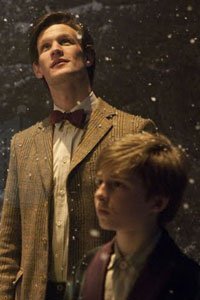The Doctor (Matt Smith) and a child stand in the snow. 